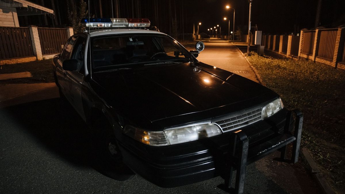 Police car with a roof light bar parked on a quiet residential street at night
